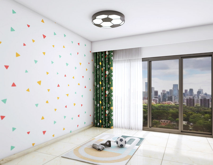 Modern kid's room with soccer-themed decor featuring a geometric triangle wallpaper, soccer ball ceiling light, sports rug, and green curtains overlooking a cityscape.