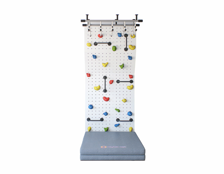 Indoor climbing wall for kids with a variety of colorful grips and a grey safety crash pad on the bottom for protection.