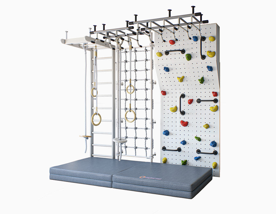 Side view of an Indoor kids' climbing setup featuring a white wall-mounted ladder, rope web, gymnastic rings, and a colorful rock climbing panel above a thick gray safety mat for active play and exercise.