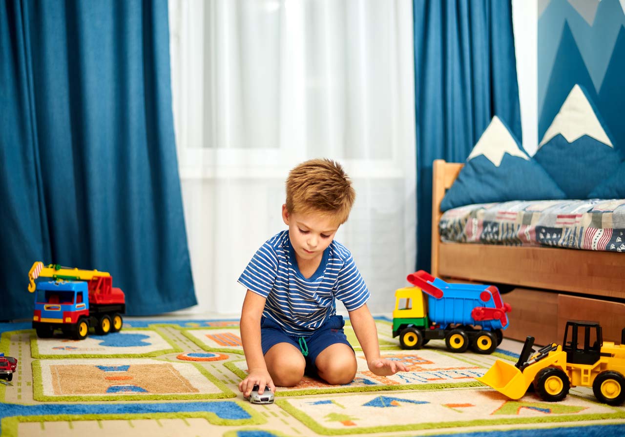 boy playing with toy car in his room