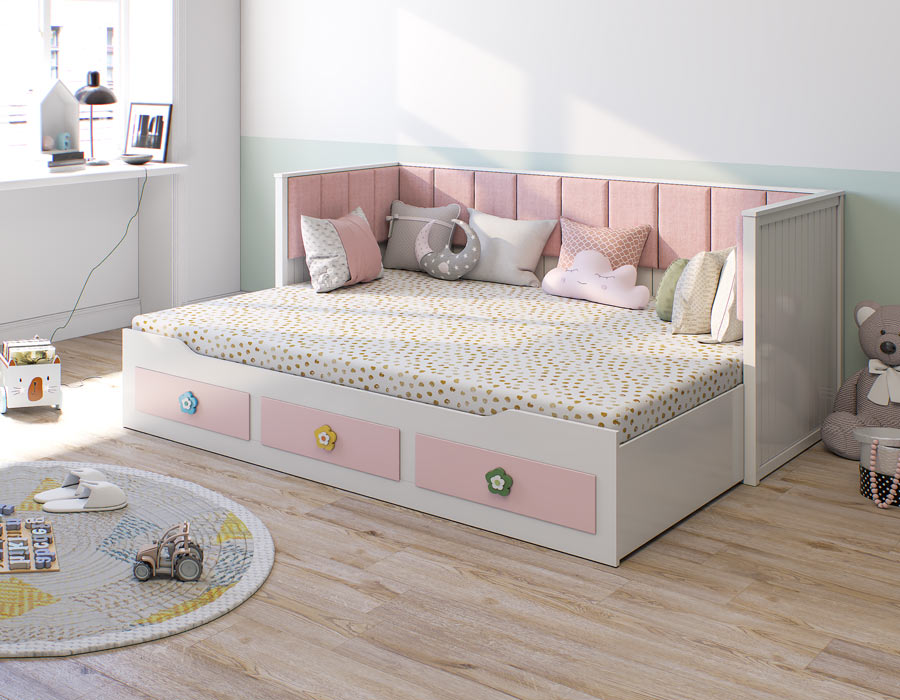A charming girl's trundle bed in soft pink and white, featuring whimsical drawer fronts and a plush, cushioned headboard.
