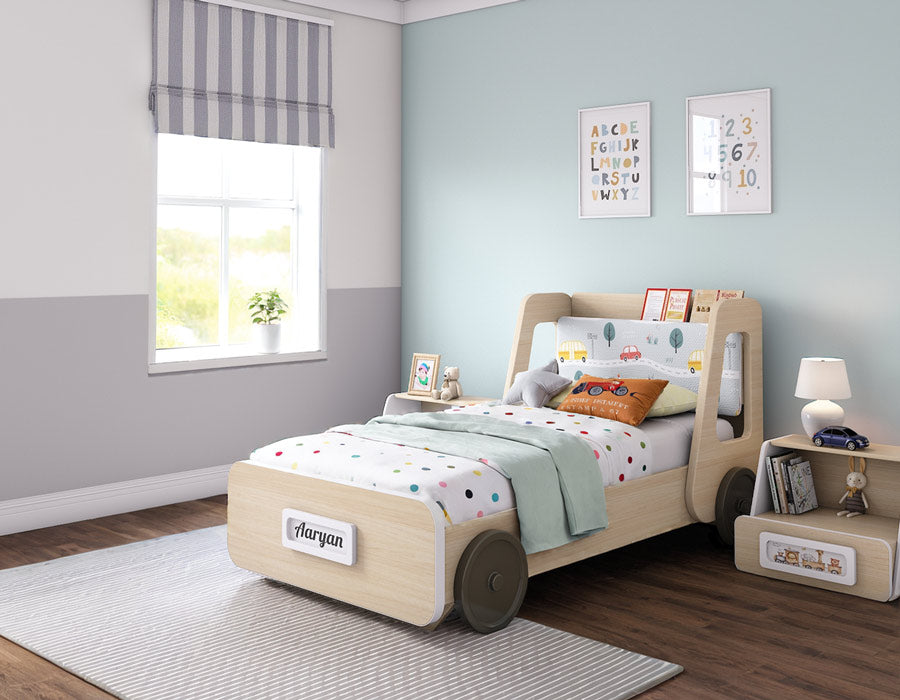 Stylish kids' room featuring a truck-themed bed with a personalized nameplate reading 'Aaryan.' The bed's headboard showcases a playful vehicle design, complemented by cozy bedding with colorful polka dots. The wooden bed frame has built-in wheels, adding a fun, transport-inspired touch. The room is decorated in soft pastel tones with a light blue accent wall, framed educational posters, and a matching bedside table holding books and toys, creating a vibrant, child-friendly space.