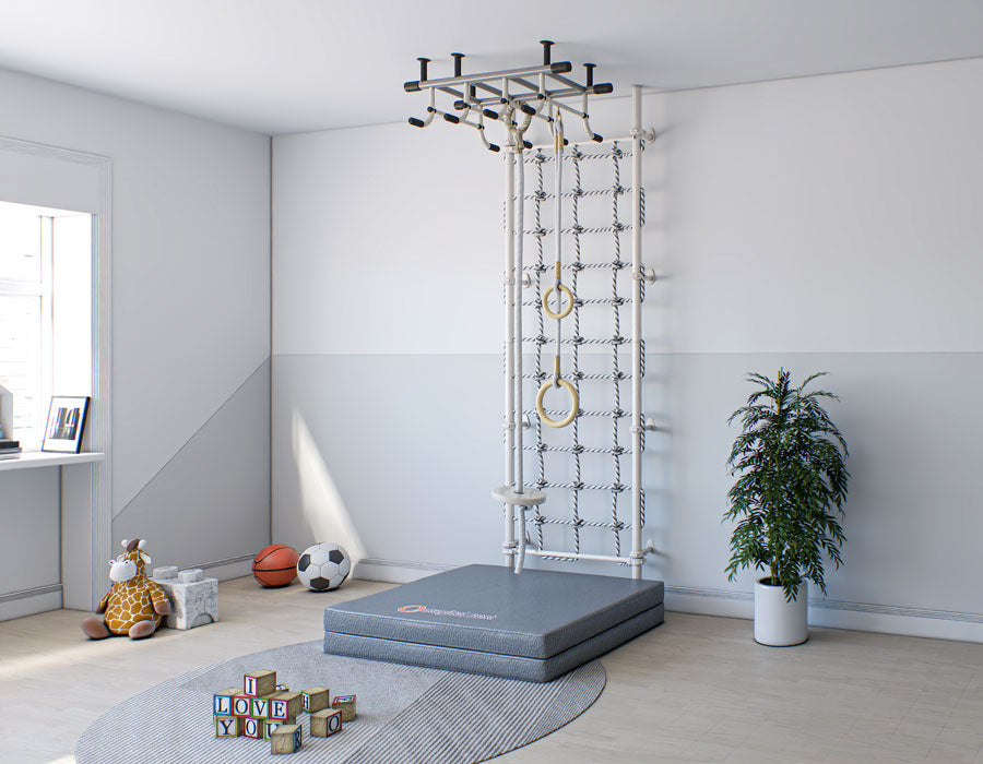 Modern kids' room featuring a white wall-mounted gymnastic rings and rope set, with a protective grey floor mat, next to a window and decorative house plants.