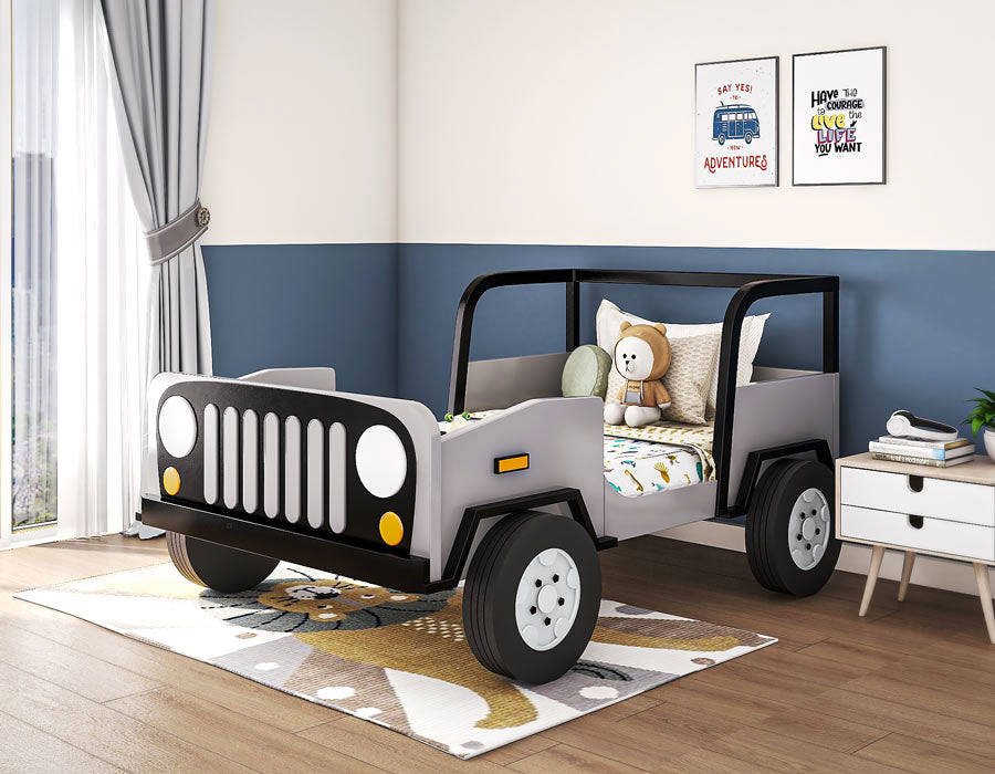 Fun and adventurous children's bedroom featuring a jeep-themed bed in grey and black, complete with realistic details like wheels and headlights. The room is bright with natural light from large windows and decorated with playful wall art, a white bedside table, and a plush teddy bear. The decor creates a lively and imaginative space for a child.