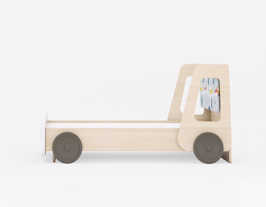 Side view of a children's wooden bed frame with a playful vehicle-inspired design. The bed features a light wood finish, rounded side panels with cutouts, and decorative wheels, giving it the appearance of a car or truck. The headboard includes a colorful vehicle-themed fabric panel, adding a fun element to the design. Ideal for a kid's room, this bed combines functionality with imaginative play.