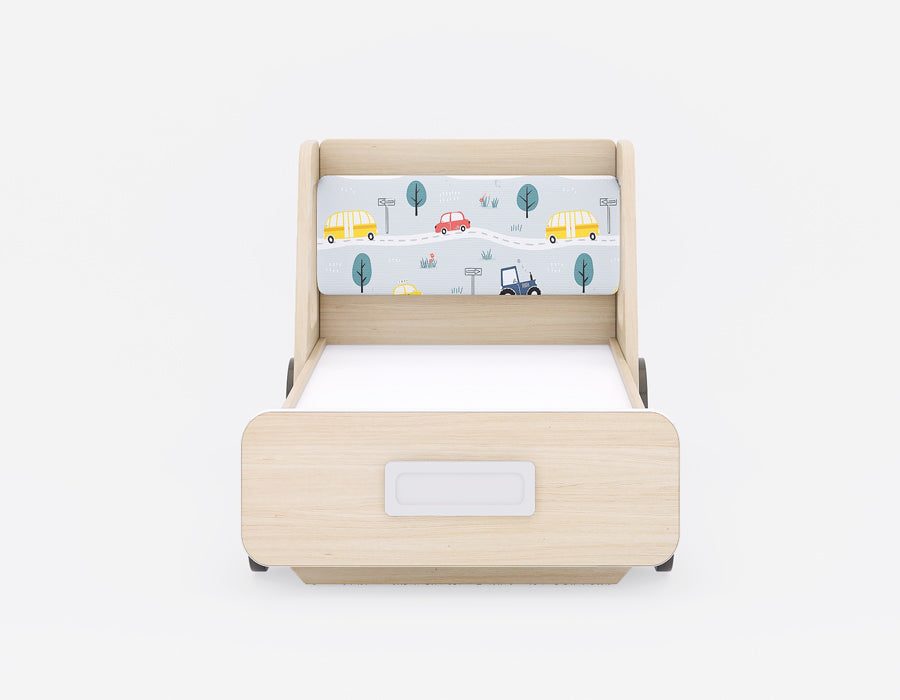 Front view of a wooden kids' bed with a playful vehicle-themed headboard. The bed features light wood tones and a colorful headboard with illustrations of cars, buses, and trees, creating a fun road trip theme. A drawer with a sleek handle is integrated into the front for added storage, combining functionality and design. Ideal for children’s rooms, blending creativity and practicality.