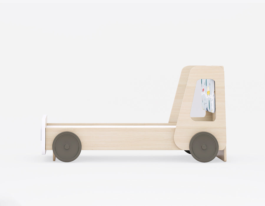 Side view of a kids' wooden truck-themed bed featuring a minimalist design with a light wood finish. The playful bed frame showcases round wheels on the sides, giving it a vehicle-inspired look. The back panel has a fun, colorful car-themed fabric insert, perfect for adding a touch of whimsy to a child's bedroom. Ideal for creating a playful yet practical space for young children.